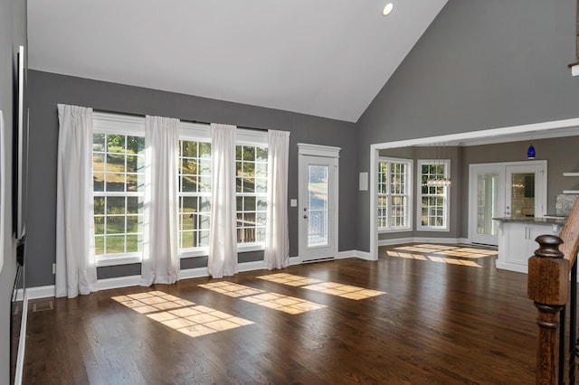 doorway with baseboards, high vaulted ceiling, and wood finished floors