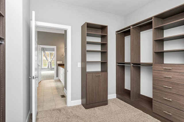 walk in closet with light tile patterned floors and light carpet