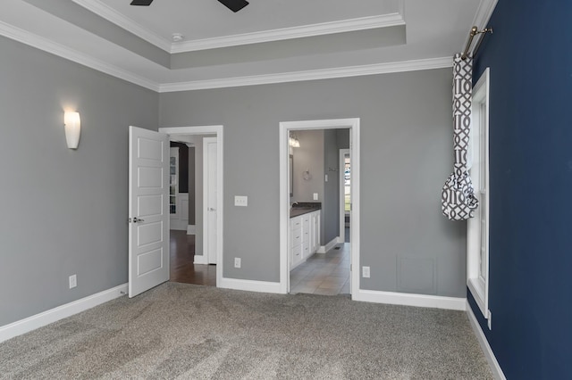 unfurnished bedroom with crown molding, a raised ceiling, baseboards, and light colored carpet