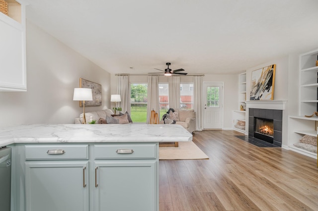 kitchen featuring a peninsula, a fireplace, open floor plan, a ceiling fan, and light wood finished floors