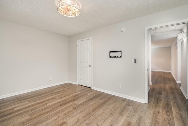 spare room with attic access, a textured ceiling, and wood finished floors