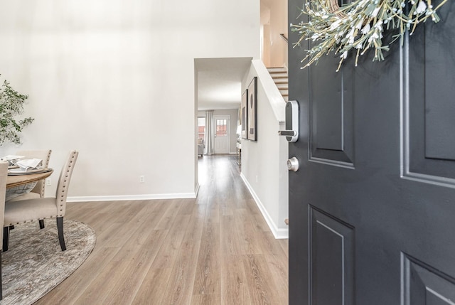 foyer featuring stairs, baseboards, and light wood-style floors
