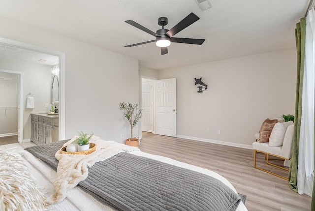 bedroom with a ceiling fan, visible vents, baseboards, ensuite bathroom, and light wood-style flooring