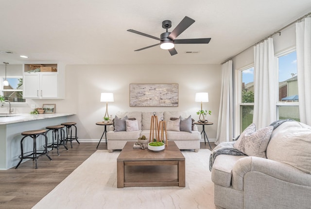 living room with a ceiling fan, baseboards, visible vents, and wood finished floors