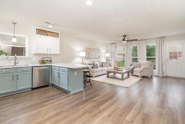 kitchen featuring a sink, a peninsula, dishwasher, and open floor plan