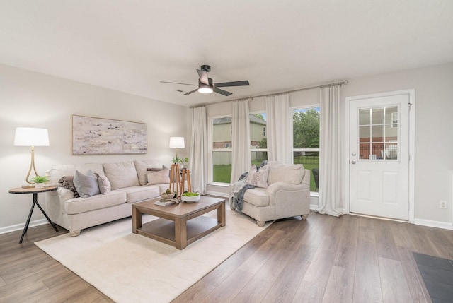living area featuring baseboards, ceiling fan, and wood finished floors