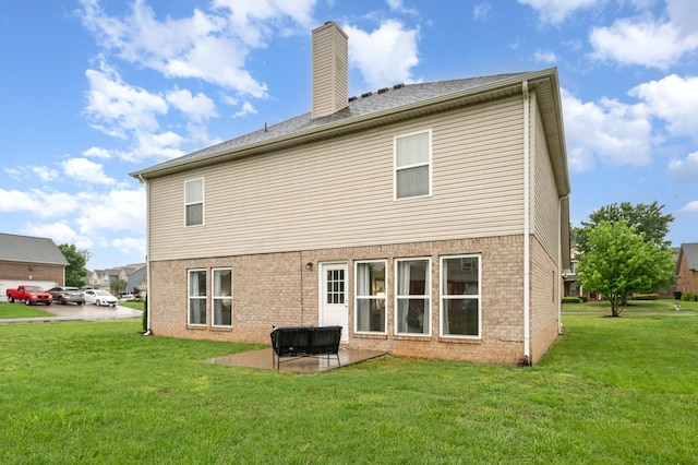 rear view of house featuring a lawn, brick siding, a chimney, and a patio