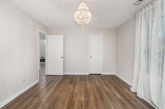 interior space featuring baseboards, dark wood finished floors, a notable chandelier, and visible vents