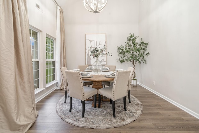 dining area with baseboards, wood finished floors, and a chandelier