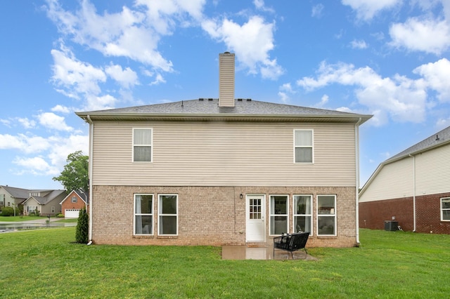 rear view of property with brick siding, a yard, a chimney, and a patio