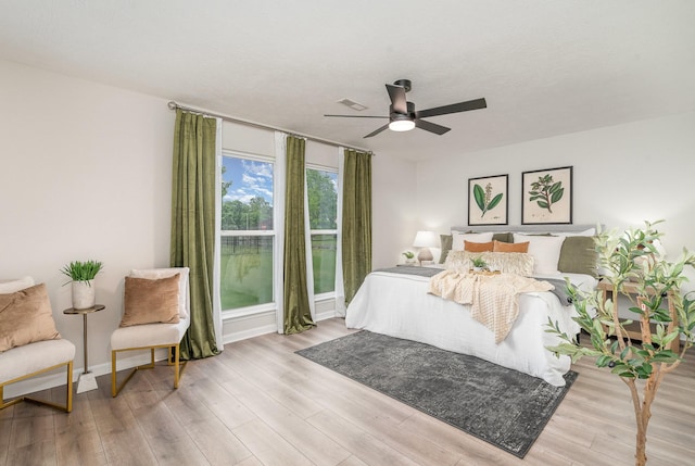 bedroom with baseboards, ceiling fan, wood finished floors, and visible vents
