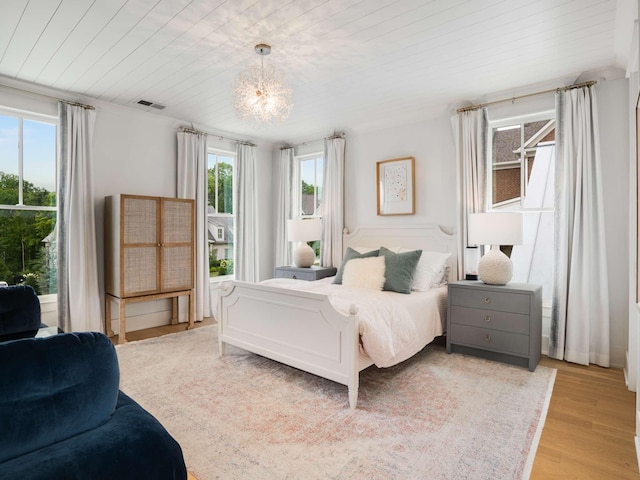 bedroom with wood ceiling, multiple windows, light wood finished floors, and visible vents