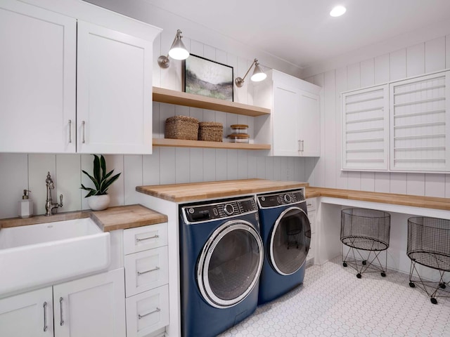 clothes washing area with a sink, separate washer and dryer, and cabinet space