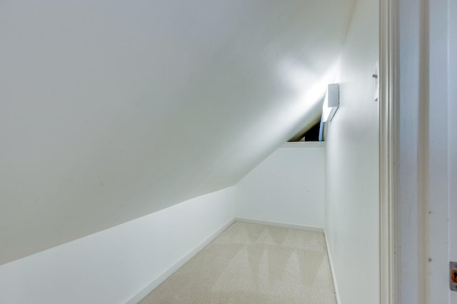interior space with vaulted ceiling and light carpet