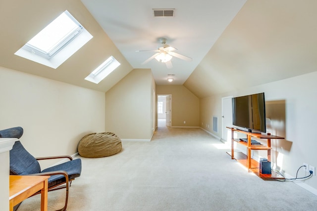 living area featuring light colored carpet, baseboards, visible vents, and lofted ceiling with skylight