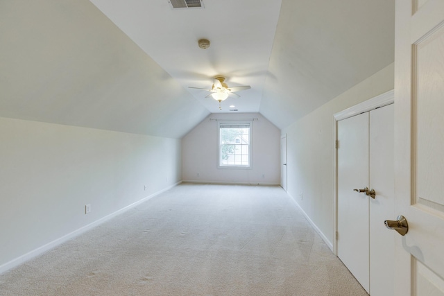 additional living space featuring light carpet, visible vents, a ceiling fan, baseboards, and vaulted ceiling
