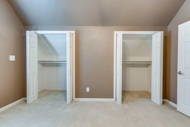 unfurnished bedroom featuring baseboards, carpet flooring, and two closets