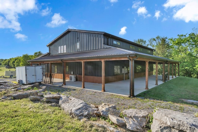 back of house featuring board and batten siding, a yard, and a patio area