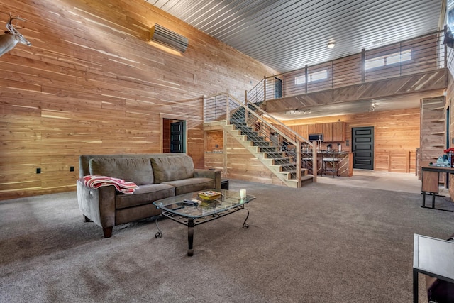 carpeted living room with wood walls, a high ceiling, and stairway