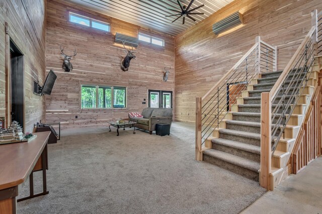 living area with a towering ceiling, wooden walls, and stairway