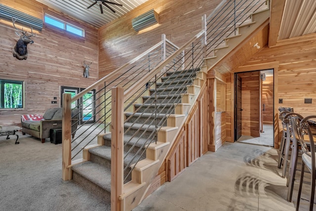 staircase featuring plenty of natural light, a high ceiling, and wood walls