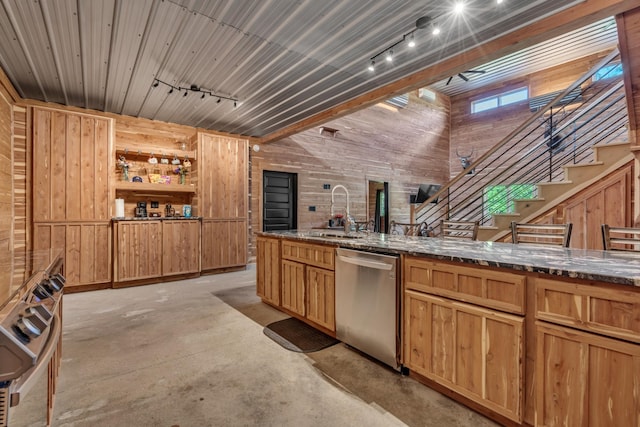 kitchen featuring stainless steel dishwasher, wooden walls, track lighting, and a sink