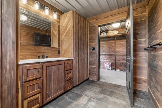 bathroom featuring vanity, wood walls, and stone finish flooring