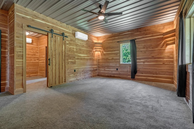 empty room featuring wooden walls, ceiling fan, and a barn door