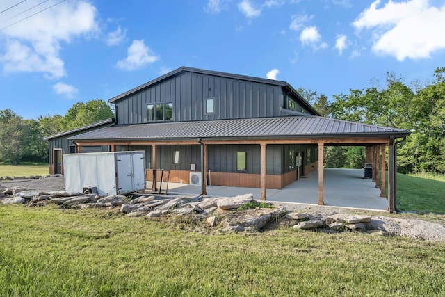 rear view of house featuring a patio, board and batten siding, a yard, and metal roof