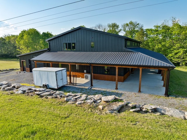back of property featuring a lawn, a patio, board and batten siding, and metal roof