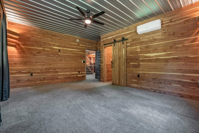 interior space with ceiling fan, an AC wall unit, wood walls, and a barn door