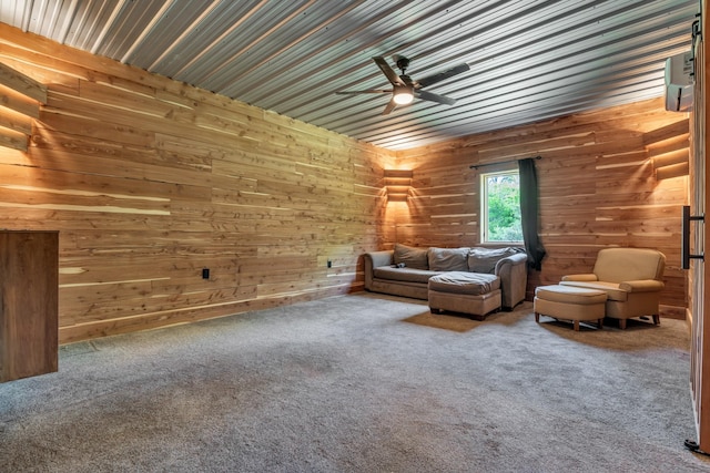 living room with carpet flooring, a ceiling fan, and wooden walls