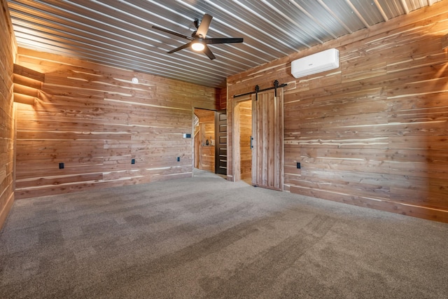 unfurnished room featuring ceiling fan, wooden walls, a barn door, a wall unit AC, and carpet flooring