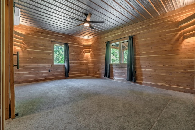 carpeted empty room with wooden walls, ceiling fan, and a healthy amount of sunlight
