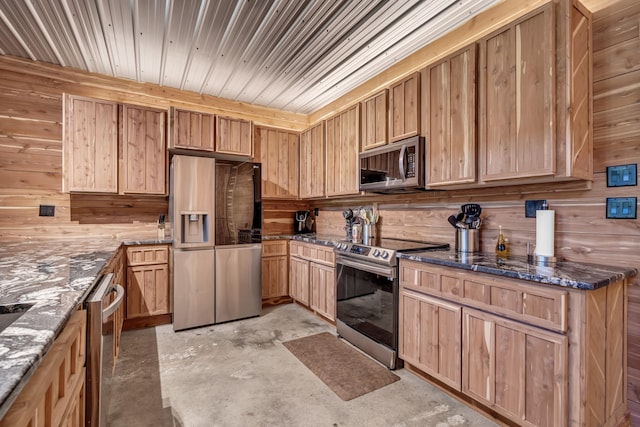kitchen with wood walls, unfinished concrete floors, and stainless steel appliances