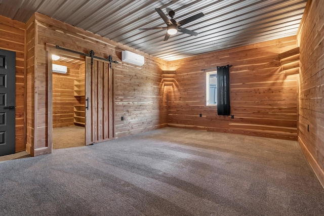 carpeted spare room with a ceiling fan, a wall mounted AC, wood walls, a barn door, and wooden ceiling
