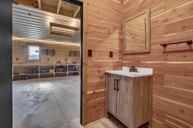 bathroom with unfinished concrete floors, vanity, and wood walls
