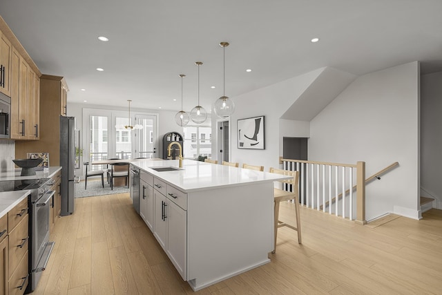 717 41st Ave N, Nashville, TN 37209 - kitchen with appliances with stainless steel finishes, a sink, light wood-type flooring, a breakfast bar area, and light countertops