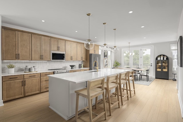 717 41st Ave N, Nashville, TN 37209 - kitchen featuring appliances with stainless steel finishes, light wood-style floors, tasteful backsplash, a kitchen island with sink, and a sink