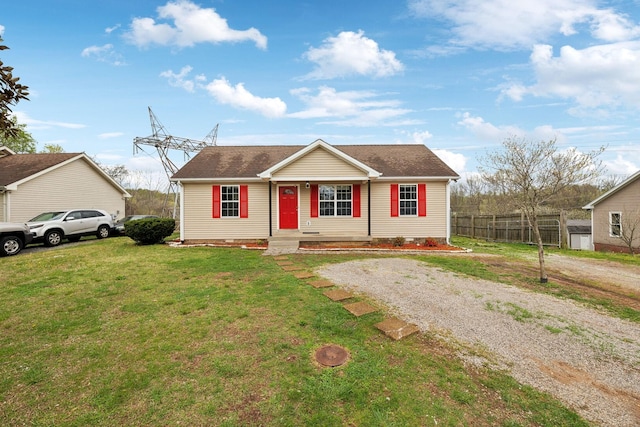view of front facade with a front lawn, roof with shingles, and fence
