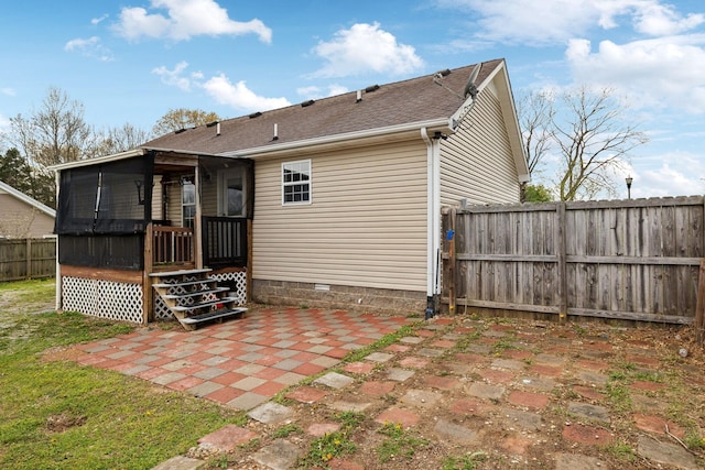 rear view of house featuring a patio, a fenced backyard, a sunroom, a shingled roof, and crawl space