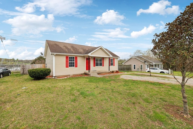 view of front of house featuring fence, roof with shingles, and a front lawn