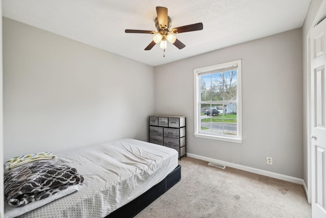 bedroom featuring baseboards, a ceiling fan, light colored carpet, and visible vents