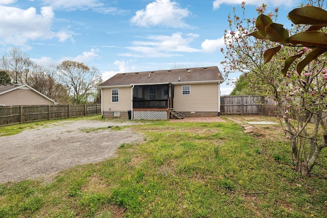 back of house featuring a lawn, crawl space, a fenced backyard, and a sunroom