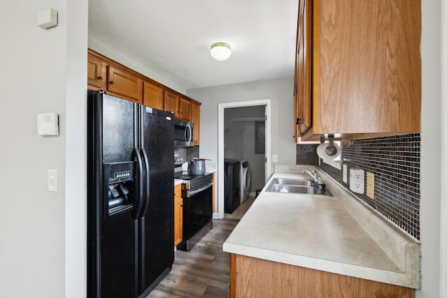 kitchen with washer and dryer, black fridge, a sink, stainless steel microwave, and range with electric stovetop