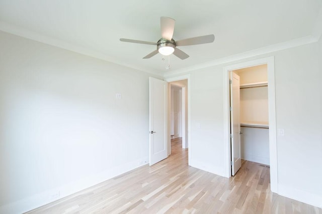 unfurnished bedroom with light wood-style floors, a walk in closet, baseboards, and a closet