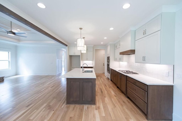 kitchen with white cabinetry, a sink, light wood-style flooring, backsplash, and stainless steel appliances
