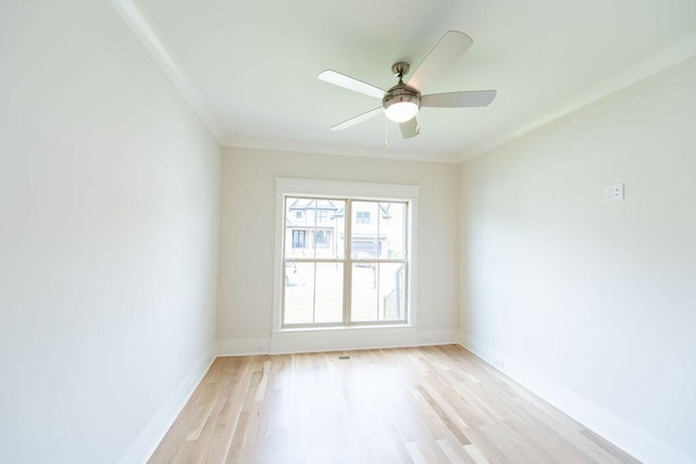 spare room featuring baseboards, a ceiling fan, light wood-style flooring, and crown molding