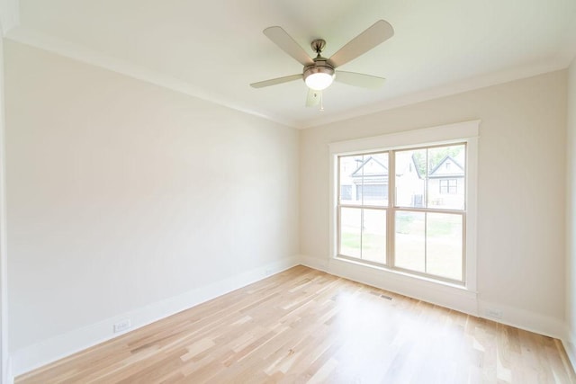empty room with a ceiling fan, baseboards, light wood-type flooring, visible vents, and ornamental molding