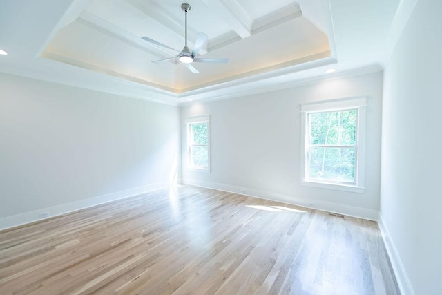empty room featuring ceiling fan, baseboards, a raised ceiling, and light wood-style floors